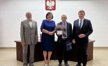 Nauczyciel z dyplomem oraz kwiatami wraz z Zarządem Powiatu