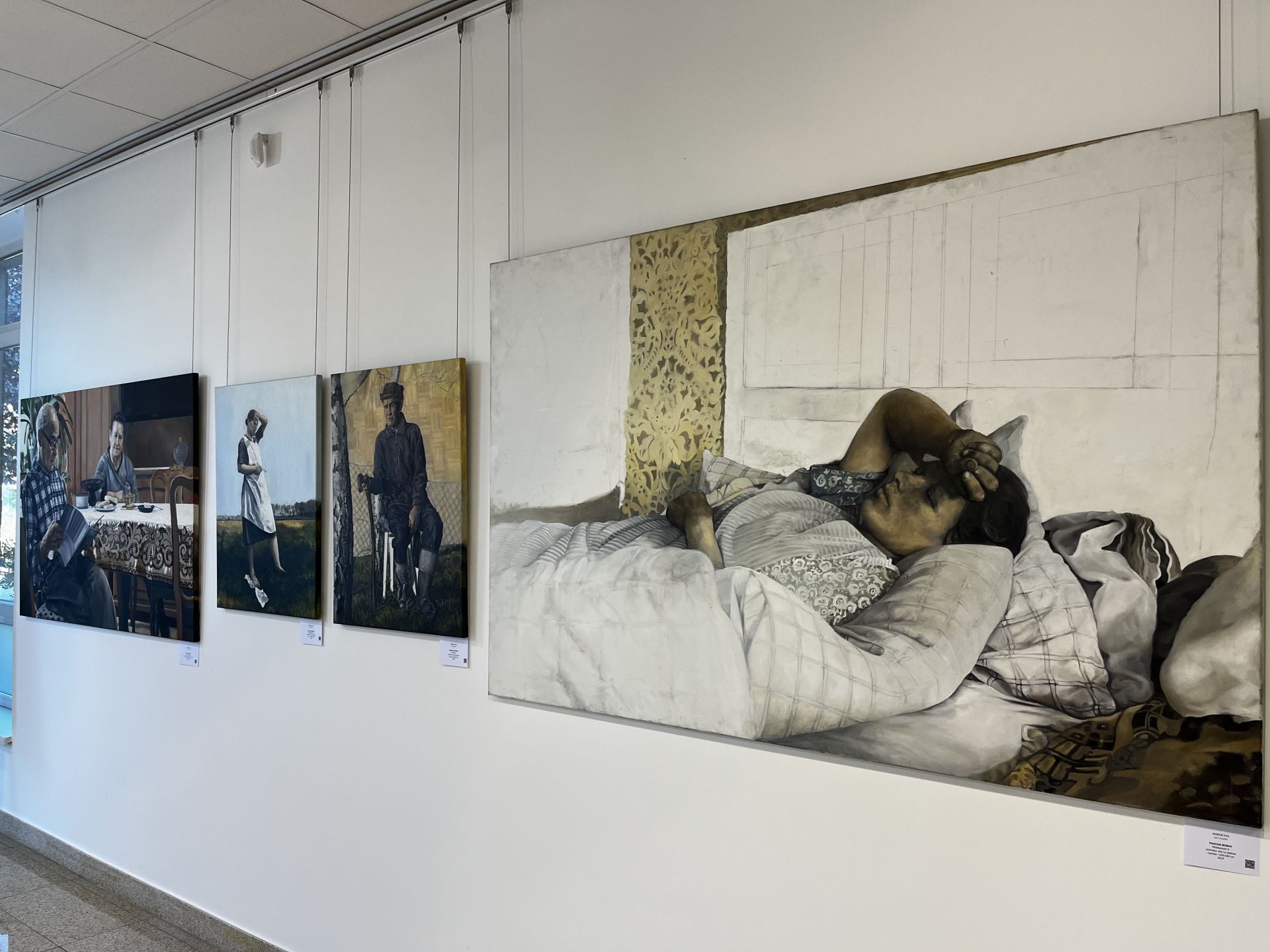 Białe ściany galerii, na której wiszą duże obrazy