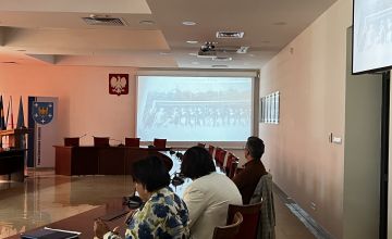 Osoby siedzące przy stole na sali konferencyjej i oglądające film Osoby siedzące przy stole na sali konferencyjej i oglądające film