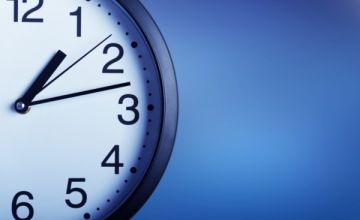 Na niebieskim tle srebrny zegar z białą tarczą