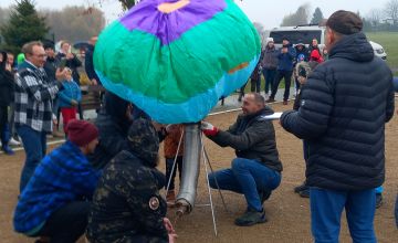 Zdjęcie przedstawiające ludzi napełniających kolorowy balon ogrzanym powietrzem